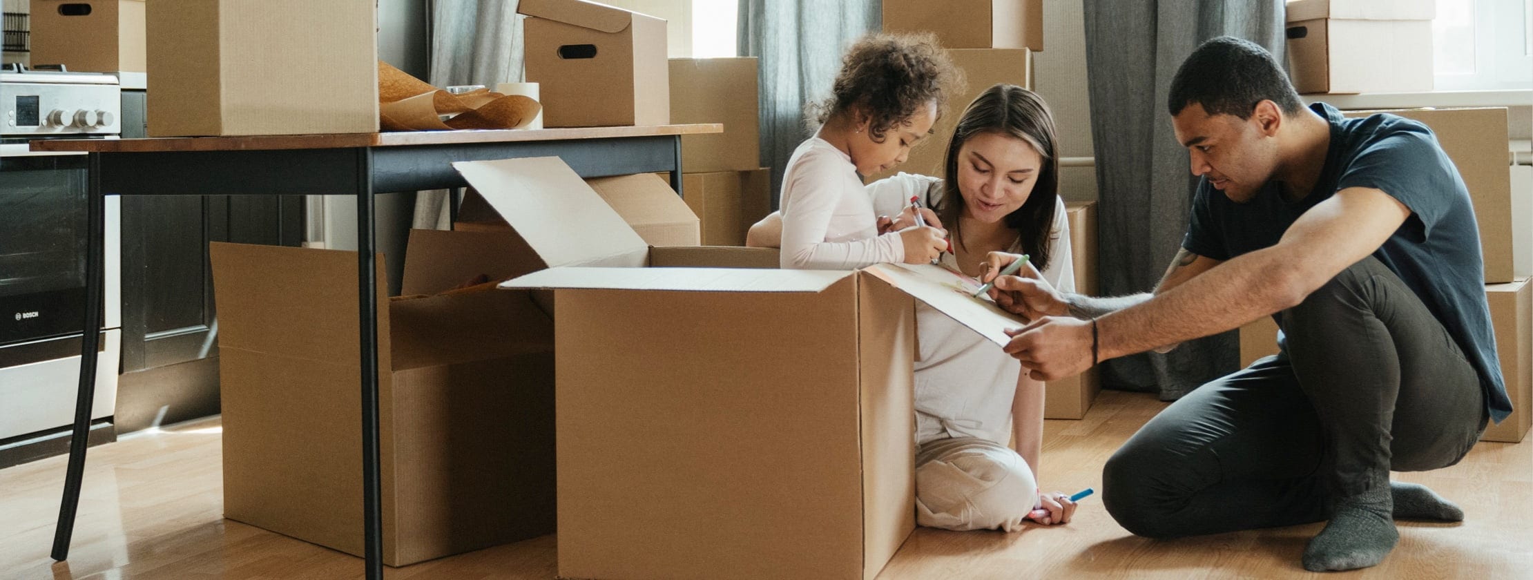 Couple with child unwrapping items from boxes in their new home